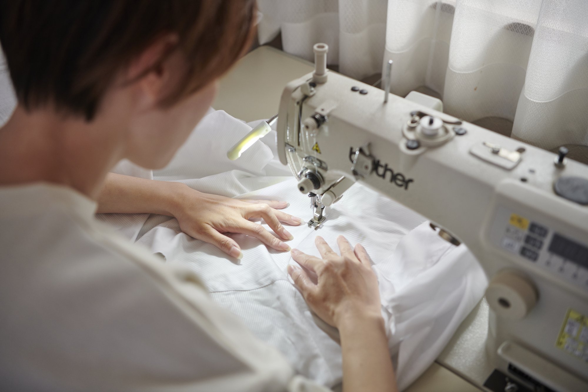 ミシンでシャツを縫製する職人の手元